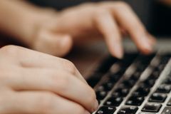 Close-up shot of hands typing on a laptop keyboard in a work environment.