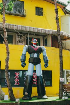 A colorful giant robot sculpture stands outside a yellow building in Seoul, South Korea.