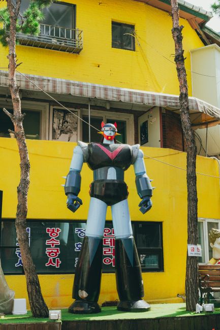 A colorful giant robot sculpture stands outside a yellow building in Seoul, South Korea.