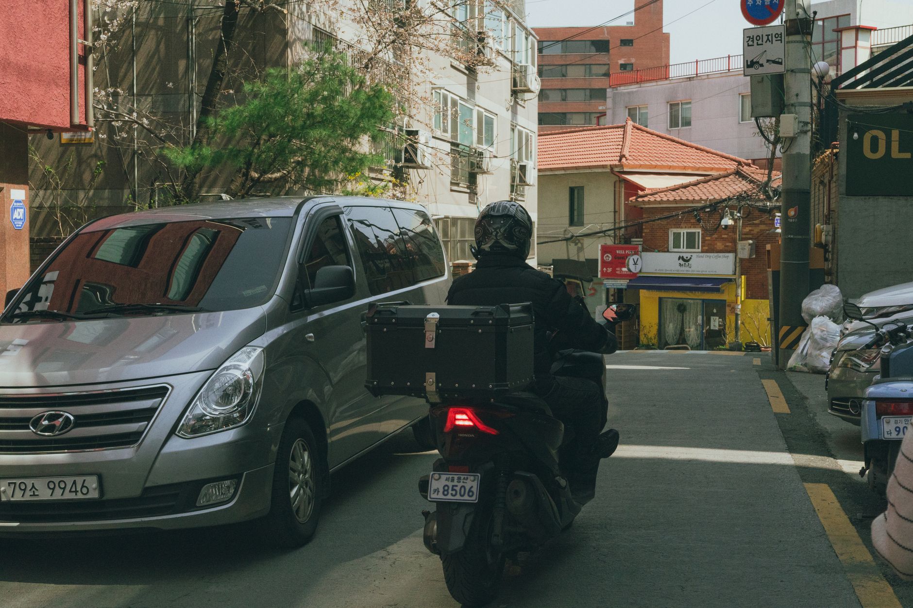 Urban scene in Seoul capturing a delivery rider in a bustling alleyway.