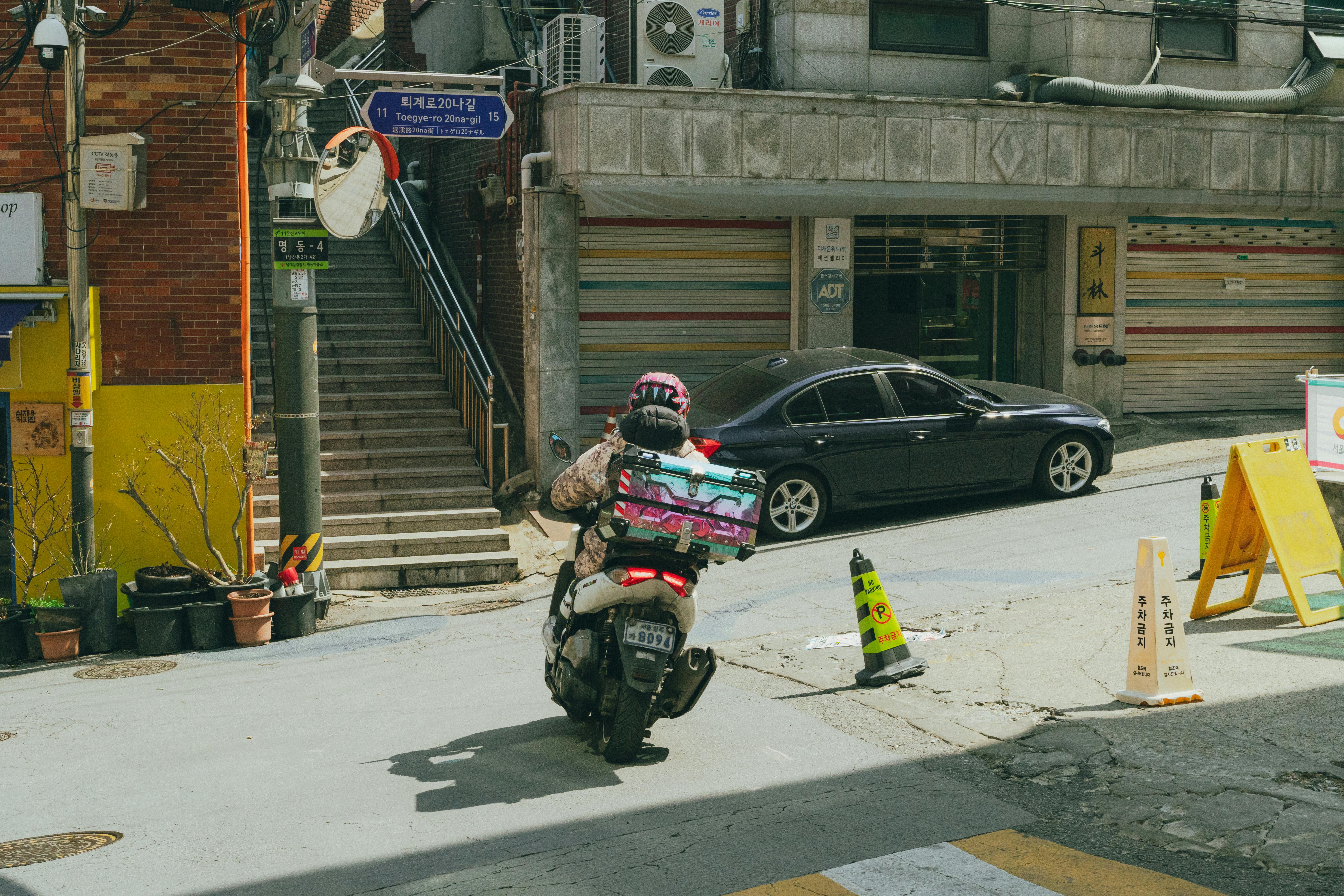 Motorbike courier navigating a busy Seoul street, capturing urban life.