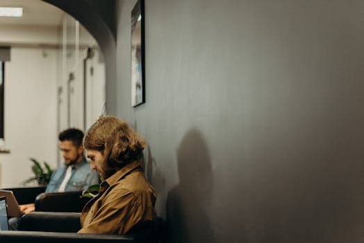 Two young men concentrating on work in a modern office environment with neutral tones.