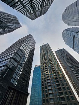 Upward view of Jakarta skyscrapers against a blue sky, showcasing modern architecture.