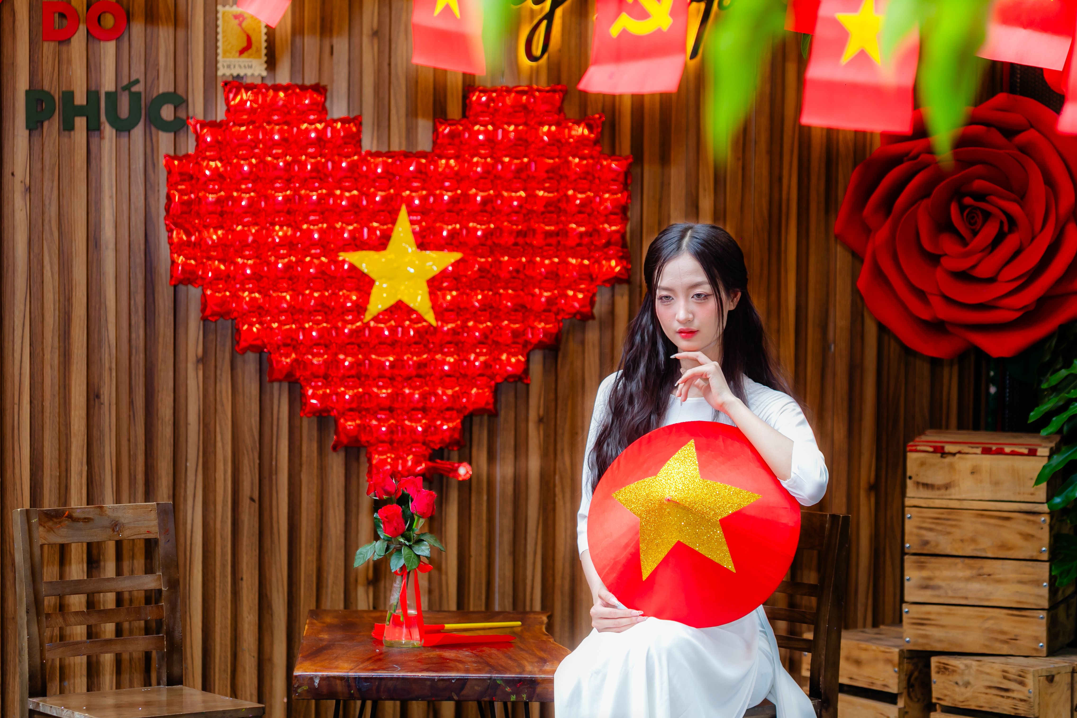 Young woman holding a Vietnamese flag decoration indoors, celebrating Vietnamese culture.