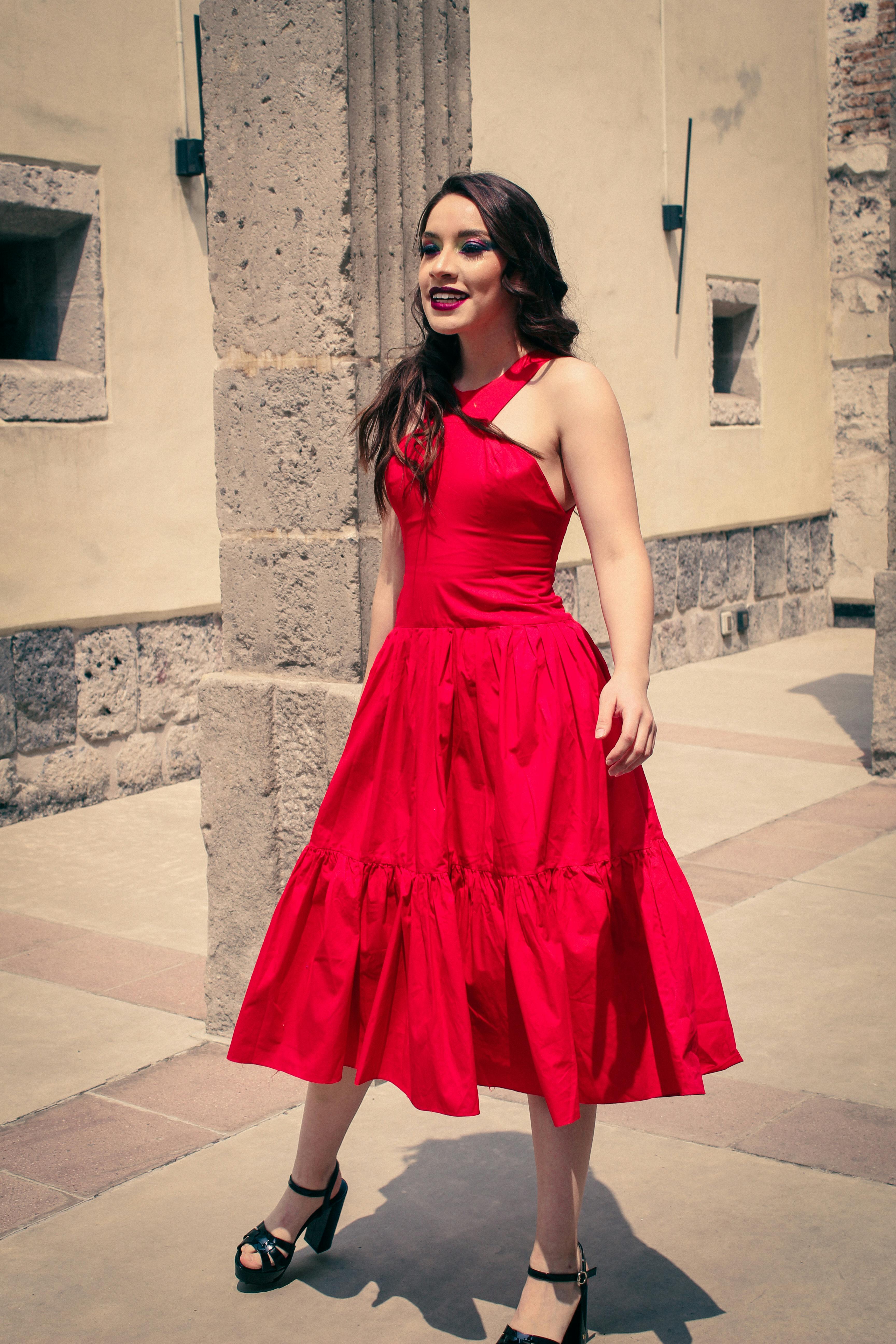 Gratis Donna alla moda che passeggia in un vivace abito rosso in un contesto urbano. Foto a disposizione