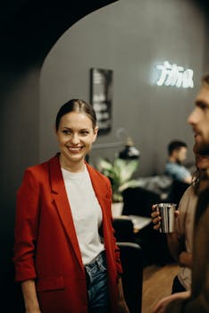 一位时尚女性穿着红色西装外套，与朋友在舒适现代的室内环境中微笑