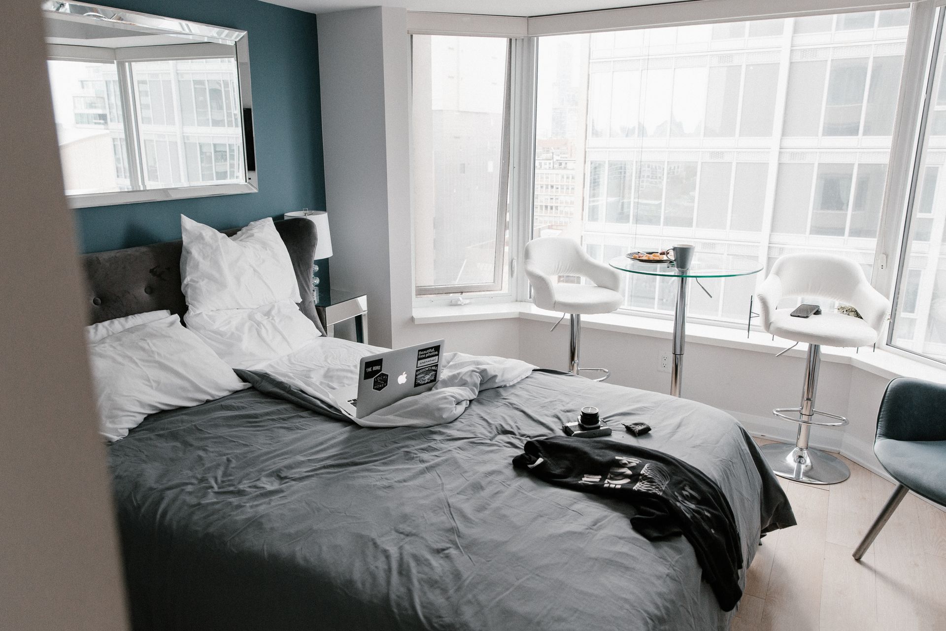 Modern hotel room in Toronto featuring a laptop, breakfast table, and city view.