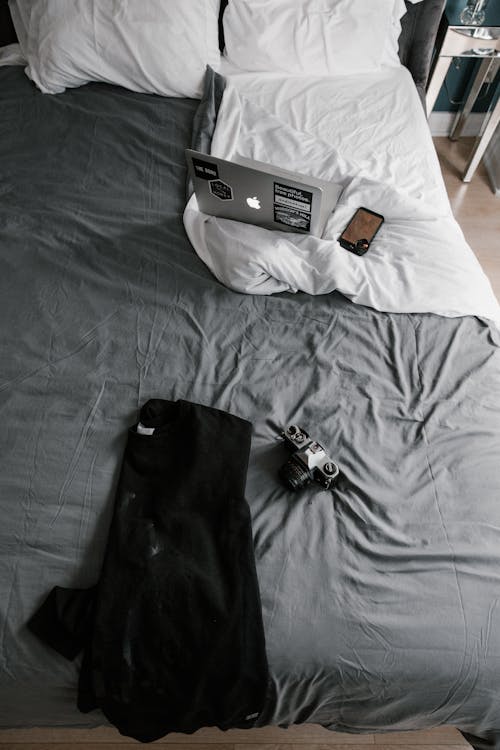 Black Jacket Beside Camera on Bed