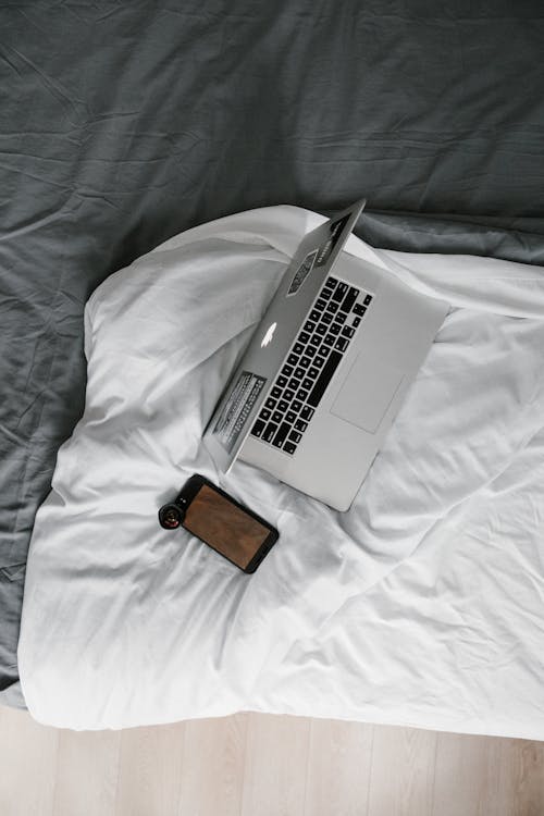 무료 화이트 침대 담요에 실버 맥북 프로 스톡 사진
