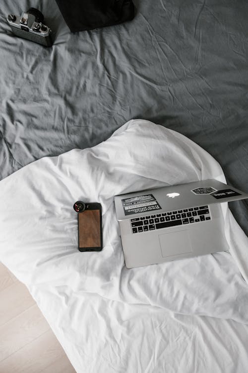 Free Macbook Beside Iphone on White Linen Stock Photo