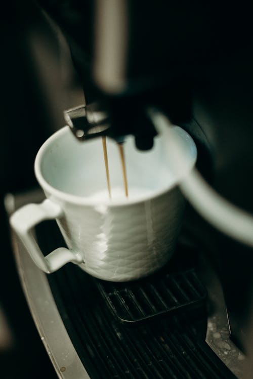 Free White Ceramic Mug With Coffee Pouring from Espresso Machine Stock Photo