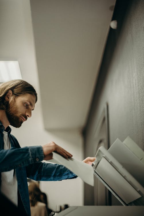 Man in Blue Denim Jacket Holding a Printing Paper