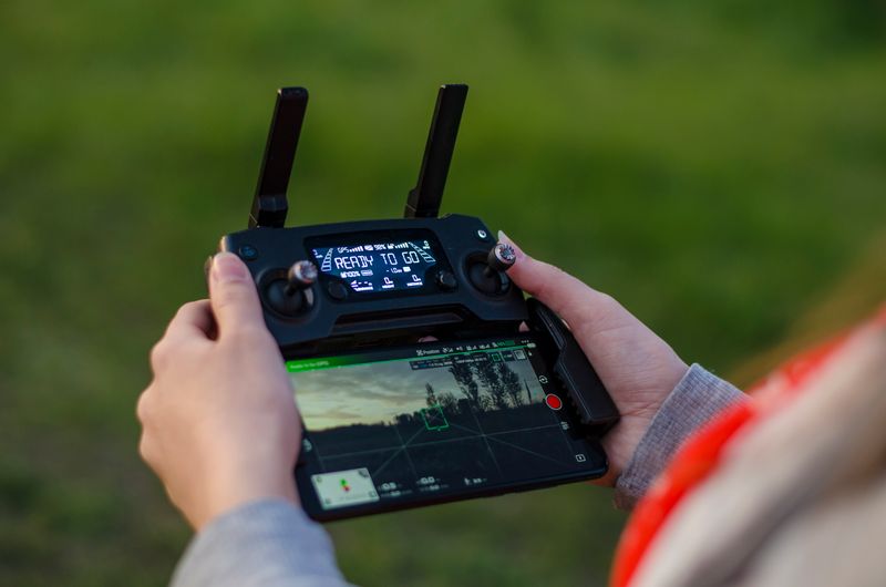 Mains tenant une manette DJI : télépilote certifié DGAC aux commandes