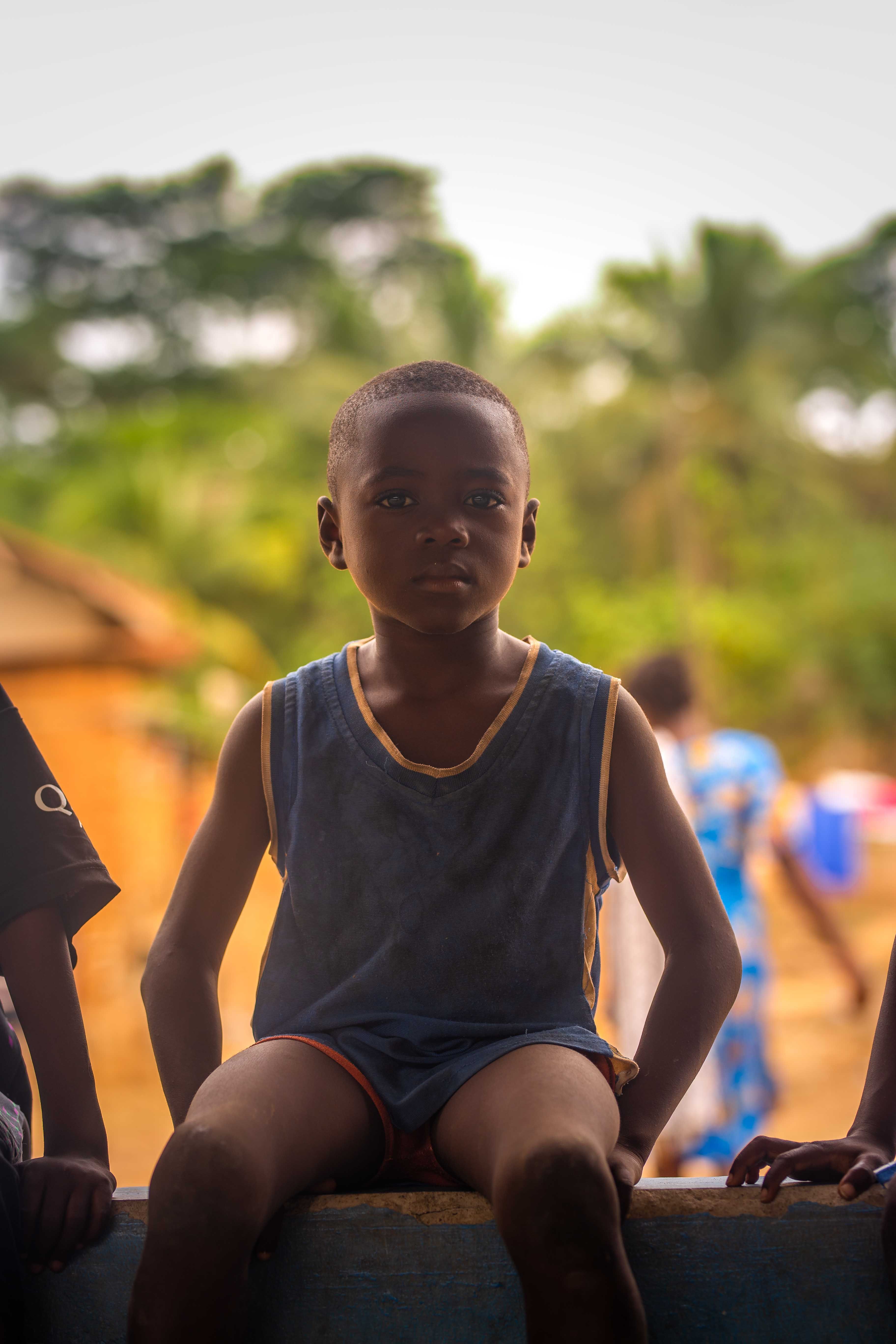 Young Boy Sitting Outdoors in a Village · Free Stock Photo