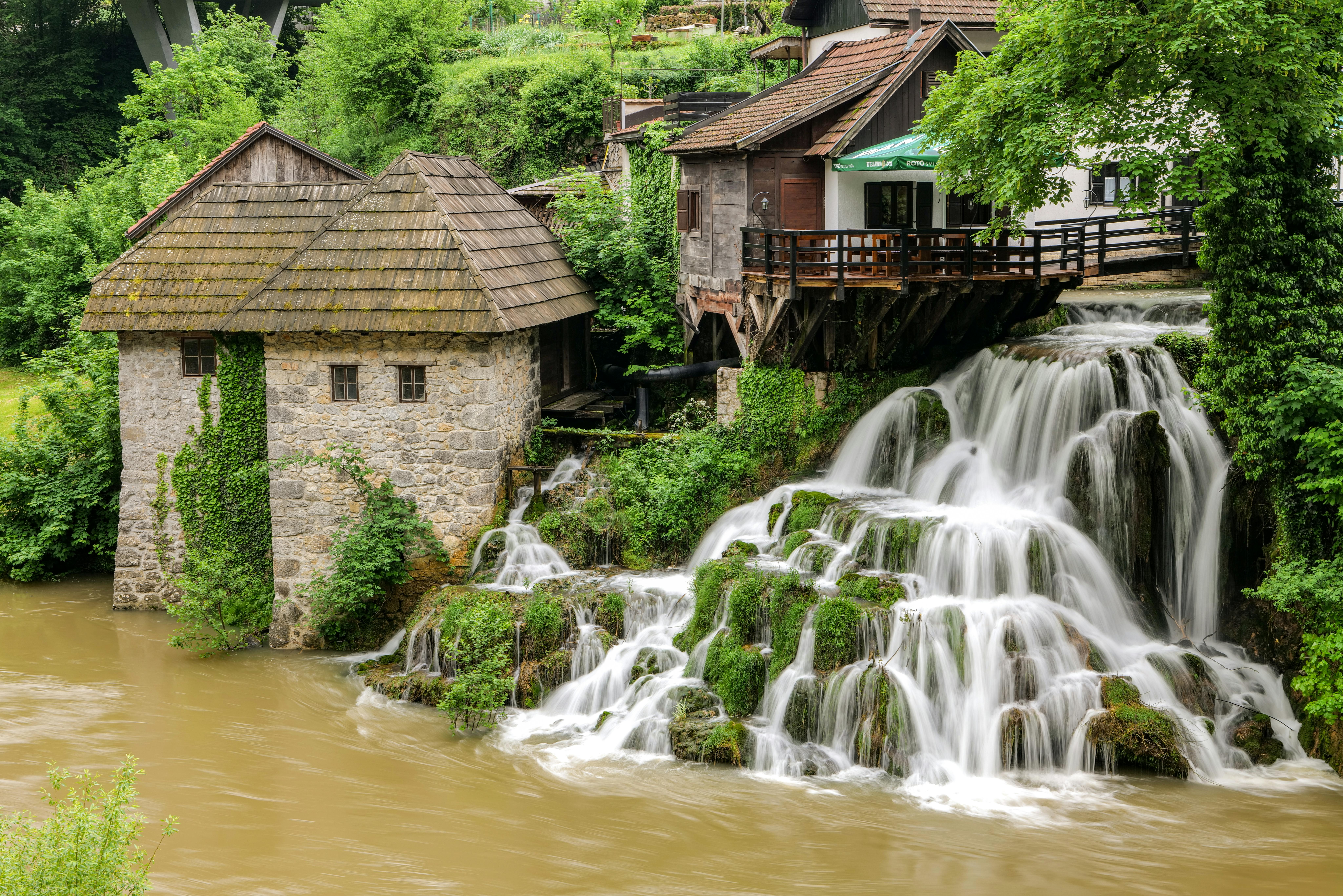 Rastoke watermills at golden hour with traditional wooden structures, travertine waterfalls, Slunjčica River cascades, and misty forests in central Croatia