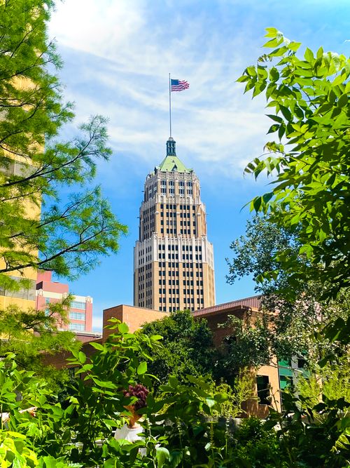 Free The historic tower rises proudly among vibrant greenery under a clear blue sky. Stock Photo