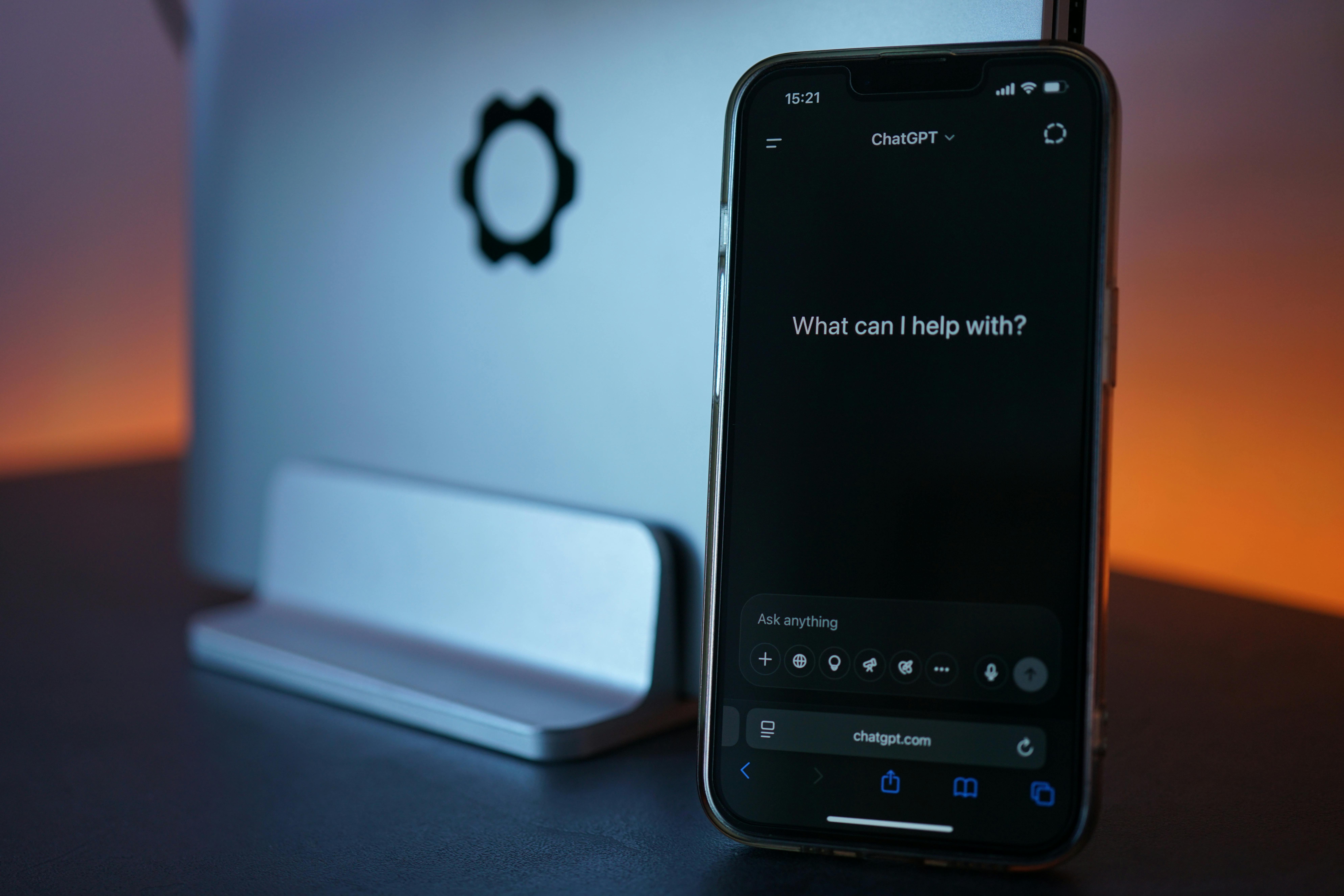 Free Close-up of a smartphone showing a chat interface with a laptop in the background. Stock Photo