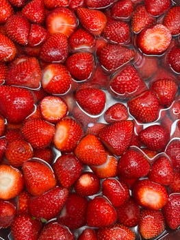 Vibrant red strawberries submerged in water, showcasing freshness and organic quality.