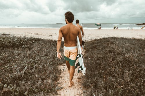 Free Man Holding Surfboard While Walking To the Beach Stock Photo