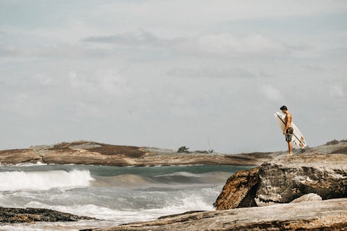 Topless Mann, Der Surfbrett Auf Brown Rock Trägt