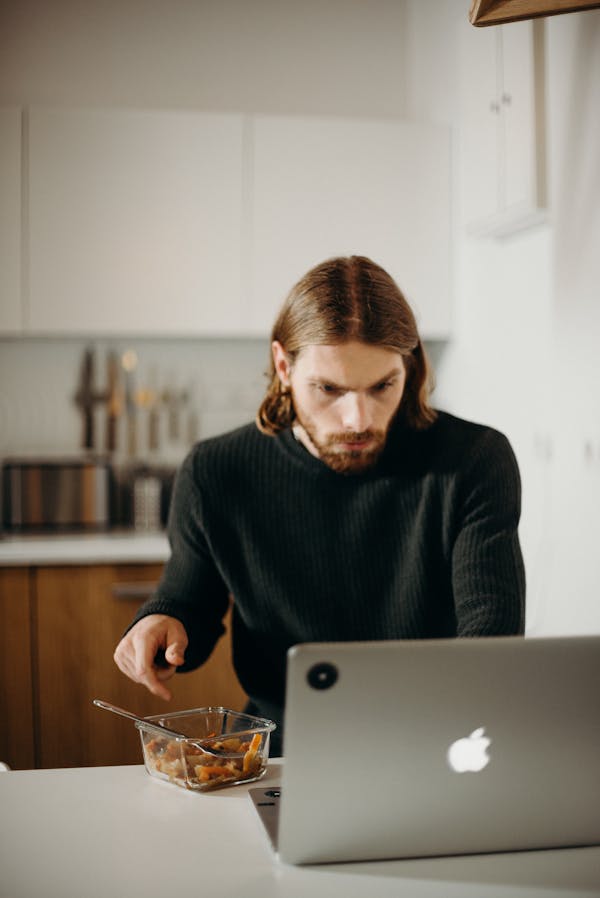 Focused remote worker in modern home office setup with multiple productivity tools displayed on screen