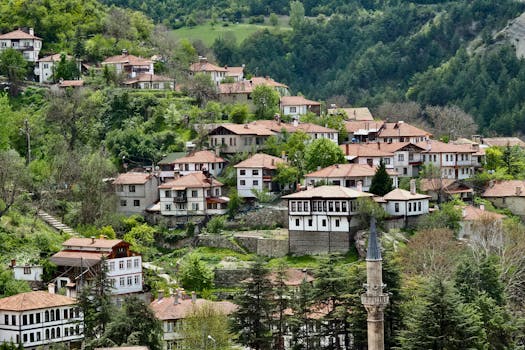 Picturesque Ottoman village nestled in lush green hills, showcasing traditional architecture with red roofs.
