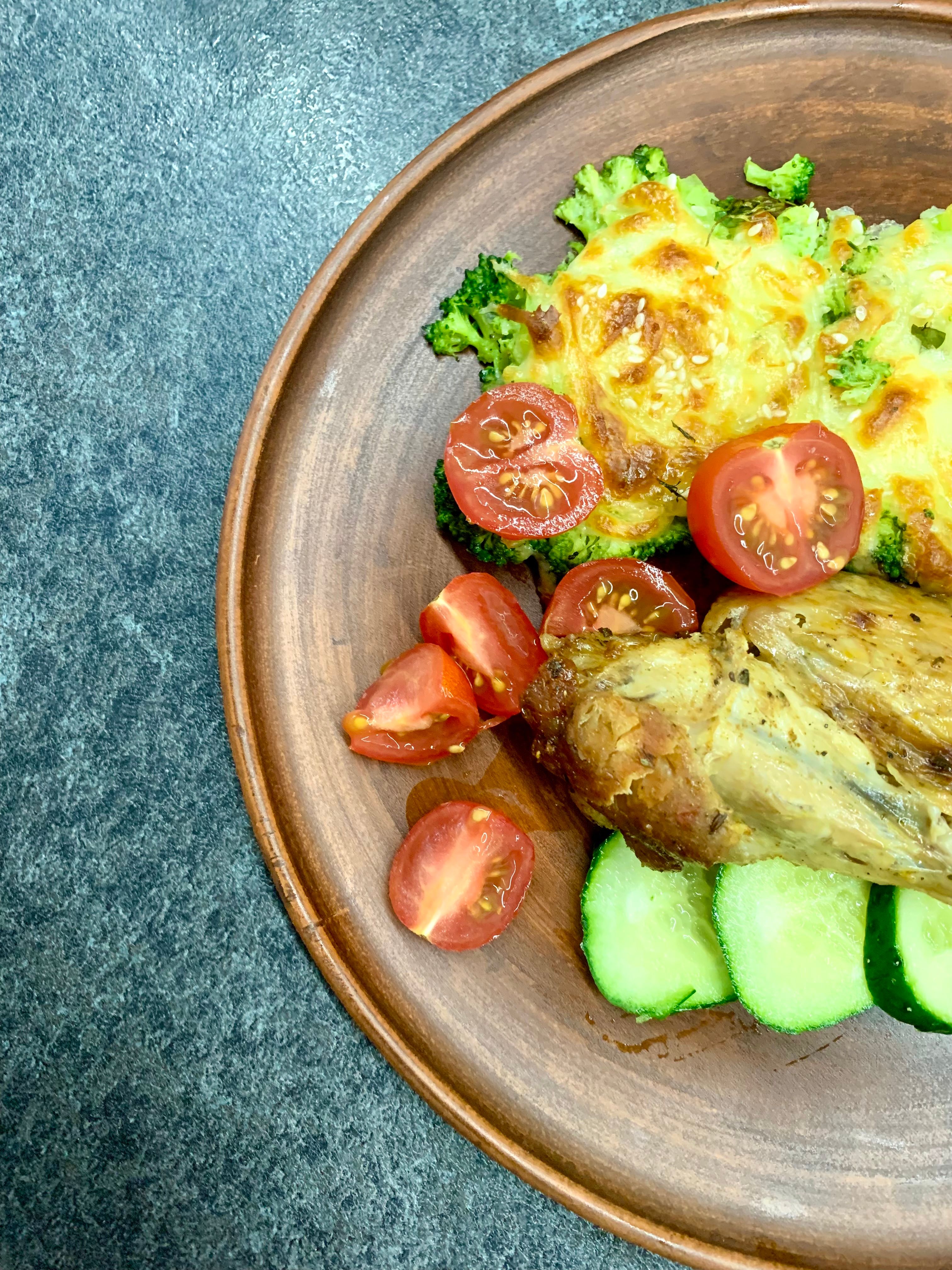 Tasty roast chicken served with fresh vegetables on a wooden plate.