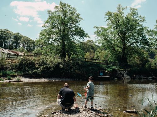 Free A serene scene of a father and son bonding by a stream in Llanfair Talhaiarn, Wales. Stock Photo