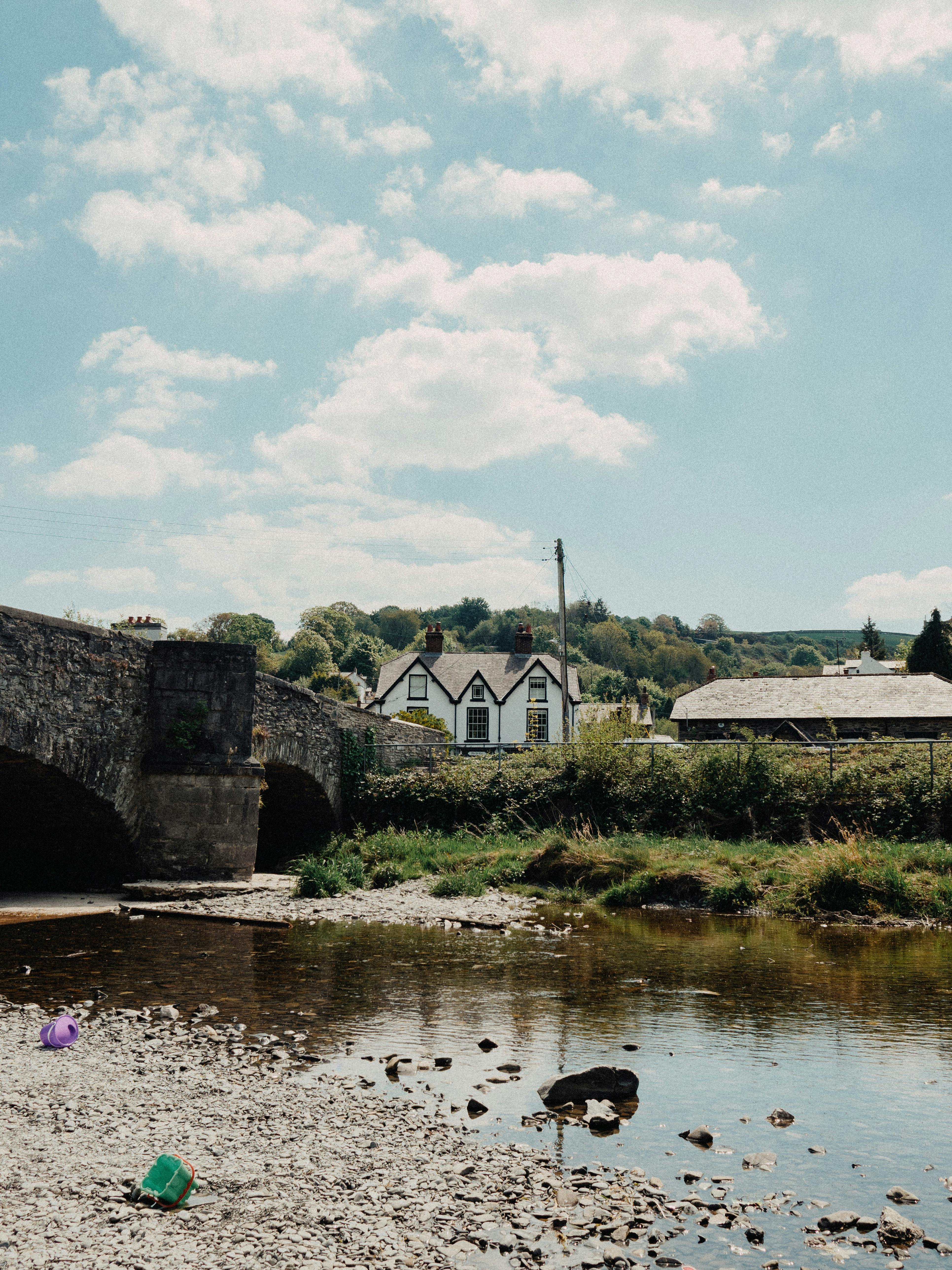 Picturesque rural scene featuring a stone bridge by the river in Llanfair Talhaiarn, Wales.