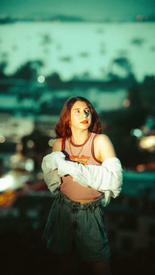 Free Portrait of a stylish woman outdoors at night with blurred city lights in the background. Stock Photo