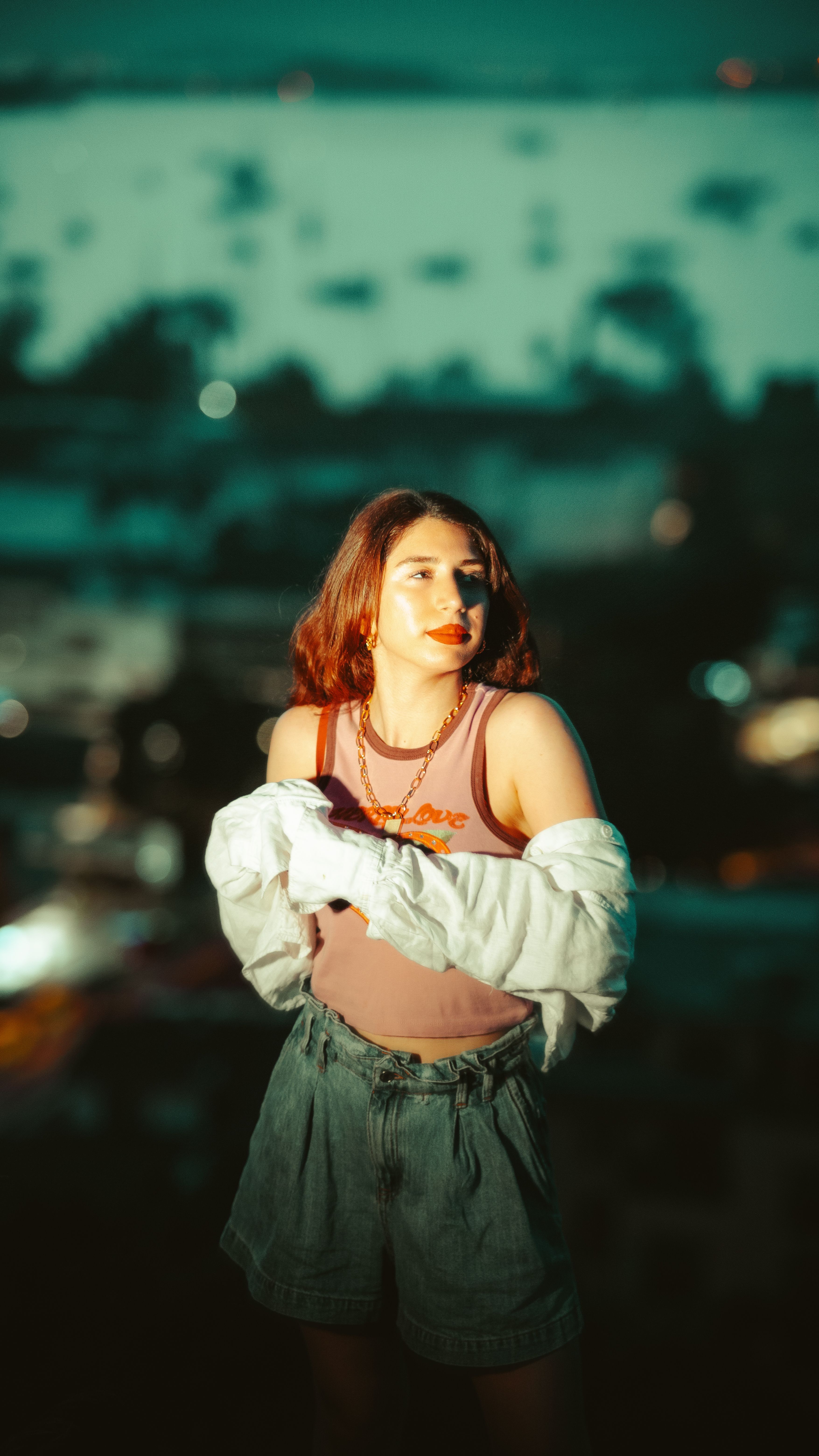 Fashionable woman in a relaxed pose at twilight outdoors with a blurred background.