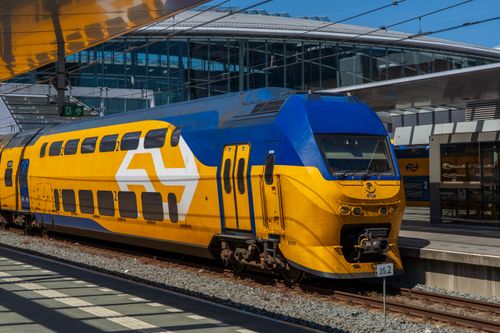 Free A bright blue and yellow intercity train at a contemporary railway station on a sunny day. Stock Photo
