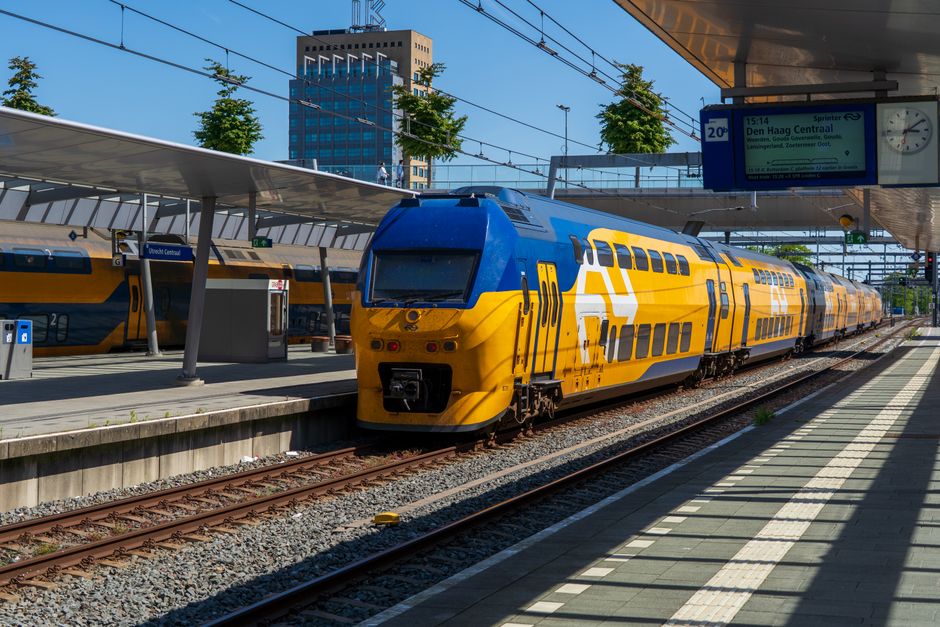 Colorful blue and yellow train arriving at Utrecht Central Station in the Netherlands on a sunny day.
