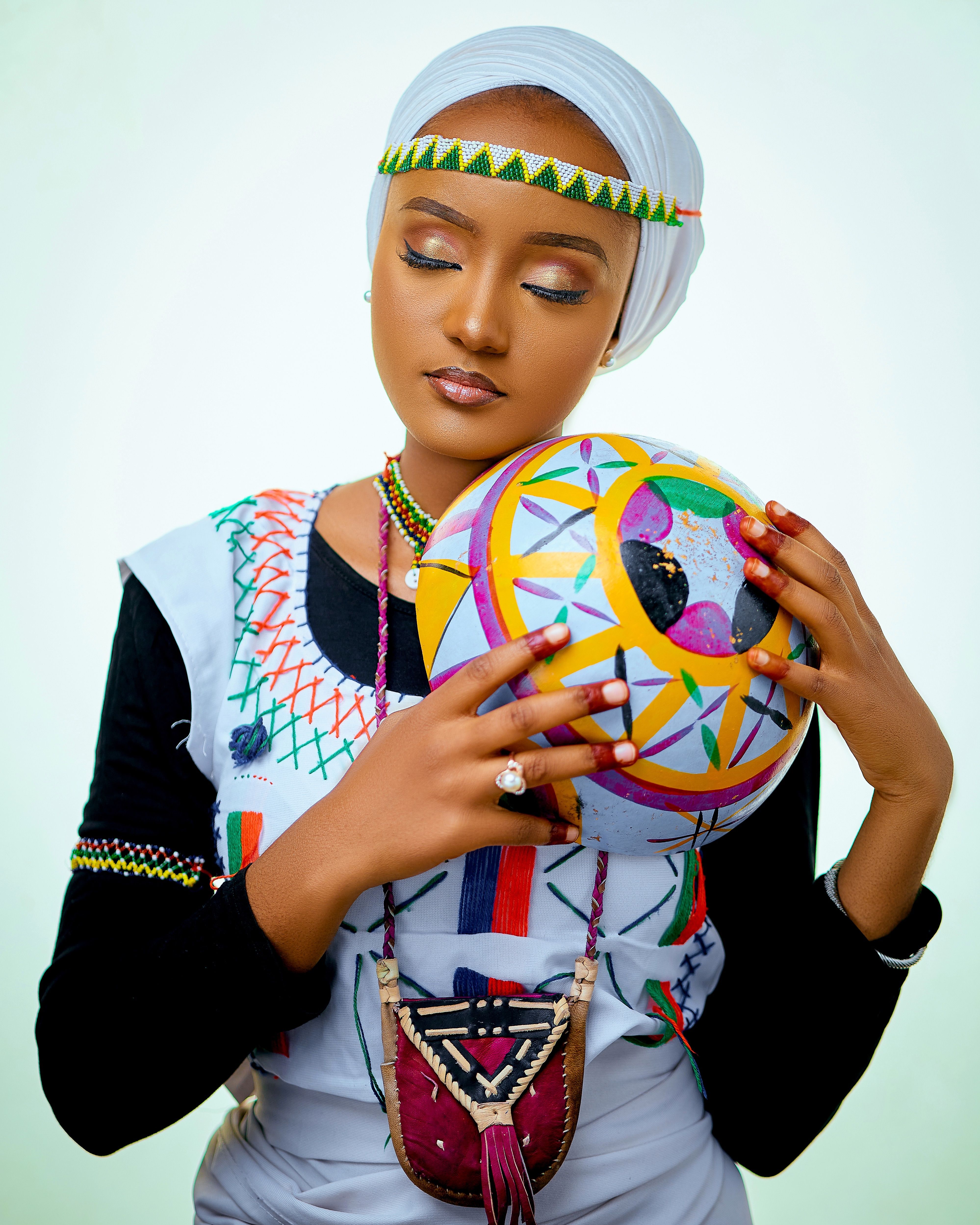 A woman in vibrant traditional attire holding a colorful ornamental ball.