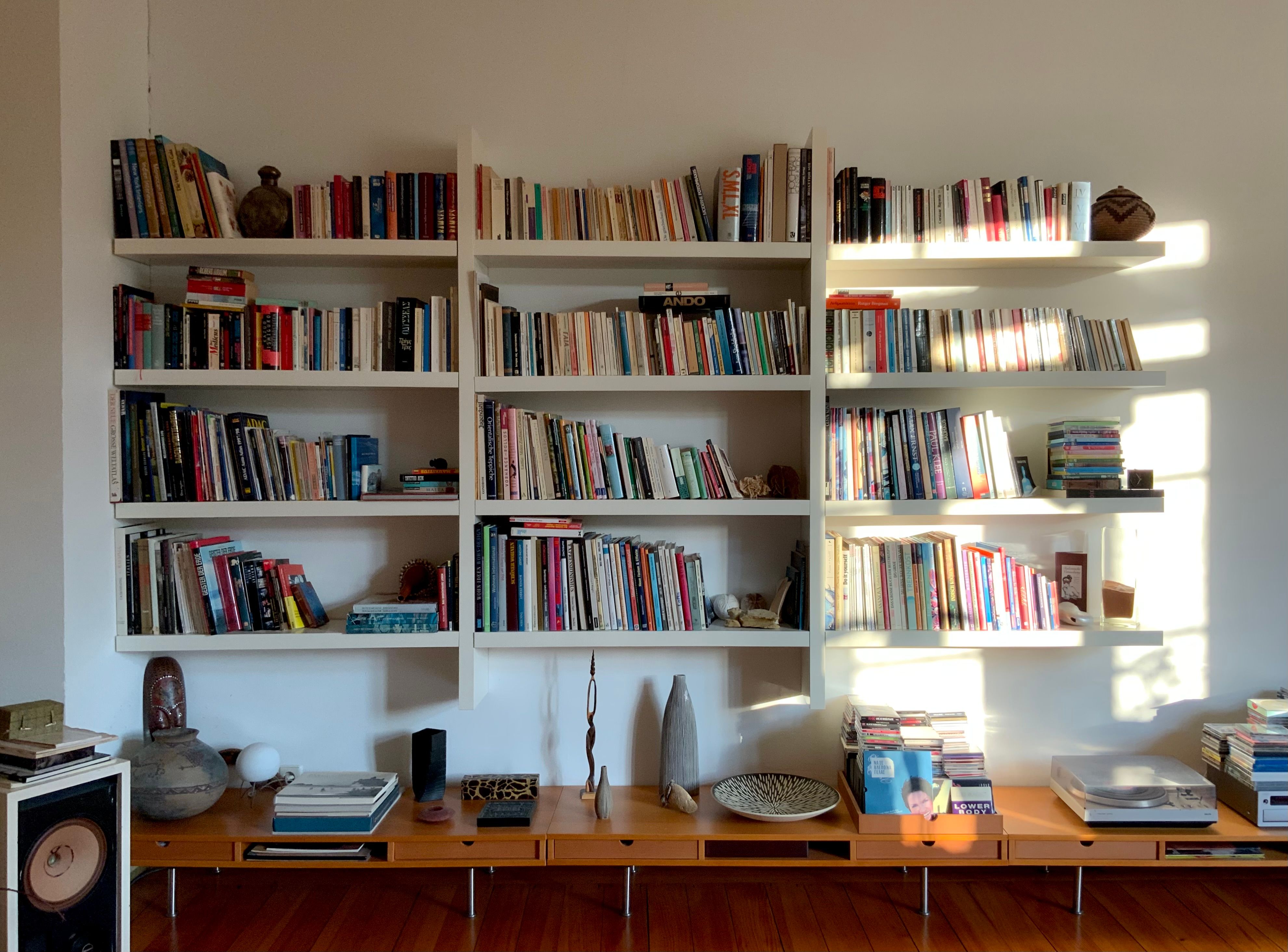 Warm and inviting home library featuring sunlit, filled bookshelves and decorative items.