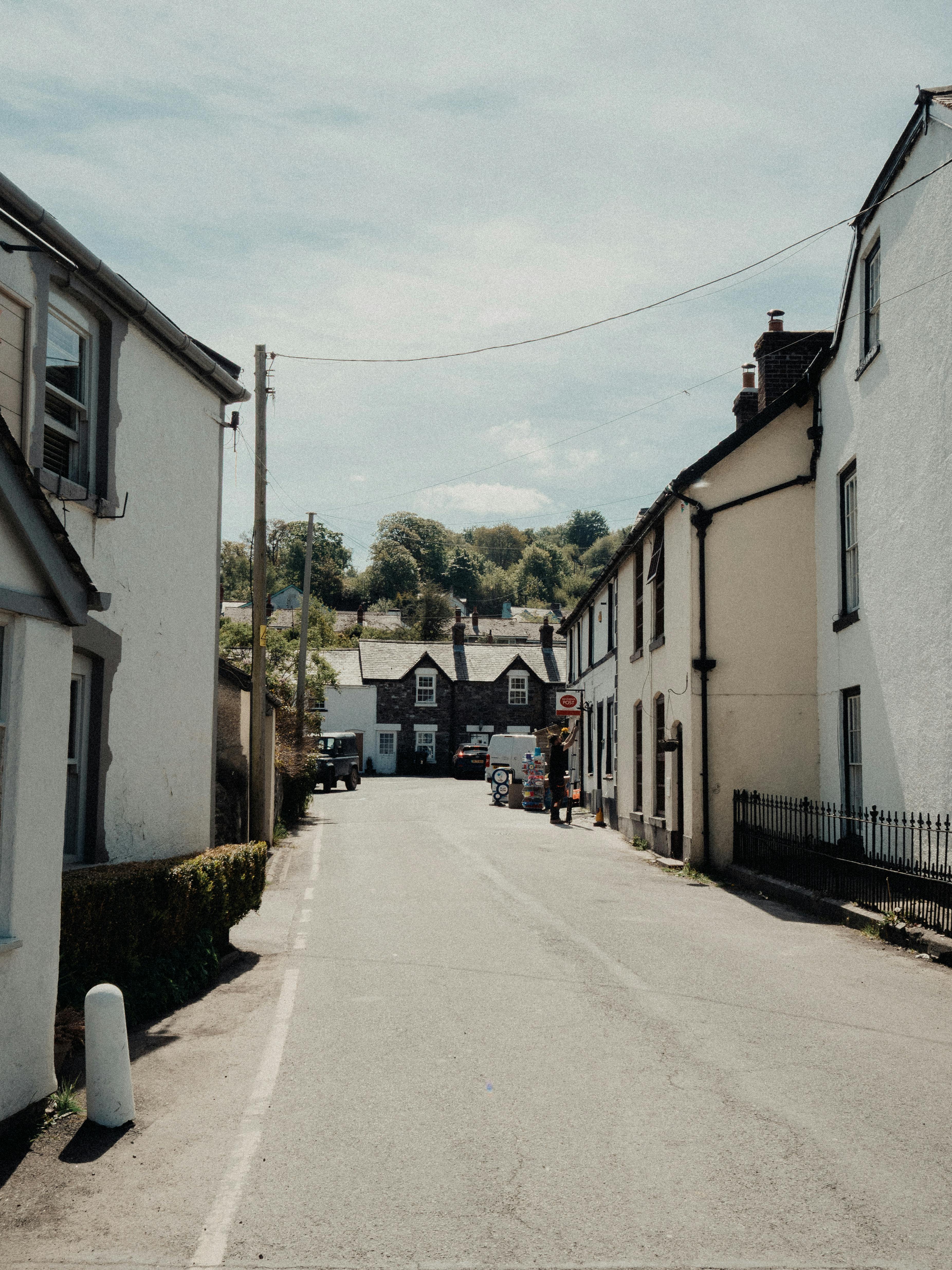 Charming village street view in Llanfair Talhaiarn, Wales with scenic countryside backdrop.