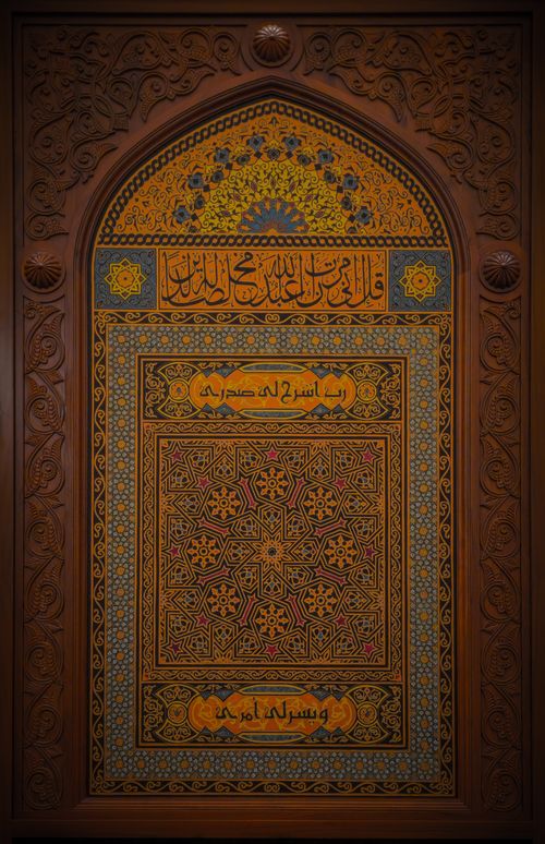 Free Beautiful Islamic calligraphy with geometric design on carved wooden panel, featuring traditional motifs and patterns. Stock Photo