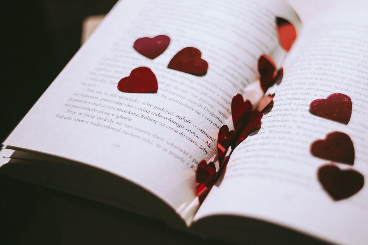 an open book adorned with red heart shaped confetti perfect for valent