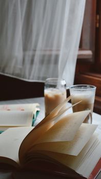 Open book by a window with coffee, perfect for cozy reading at home.
