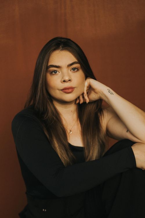 Free Close-up of a young woman with relaxed expression on a warm brown backdrop. Stock Photo