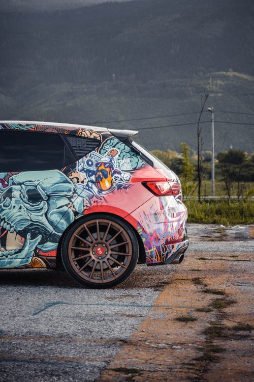 Free Customized hatchback car with graffiti art parked against a scenic mountain backdrop in Sarajevo. Stock Photo