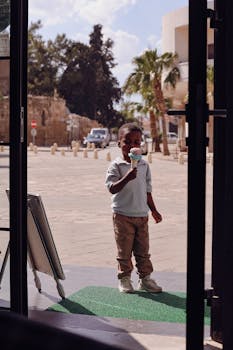 Young boy savoring an ice cream cone outside a shop on a sunny day.