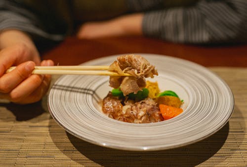 Free Enjoy a gourmet meal featuring tender meat and vibrant vegetables in Kamogawa, Japan. Stock Photo