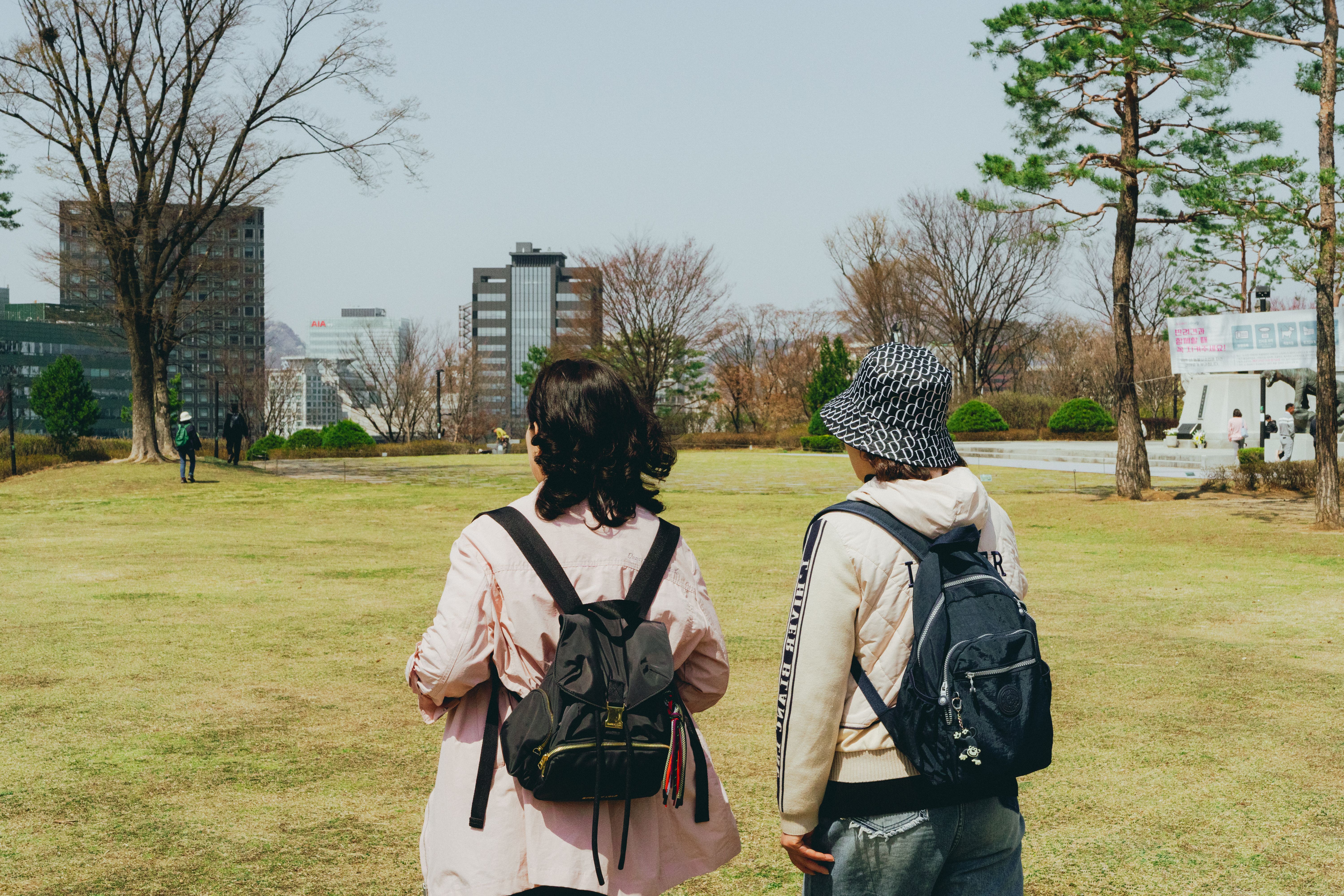 Two people strolling in a park in Seoul, South Korea during springtime, capturing the city's blend of nature and architecture.