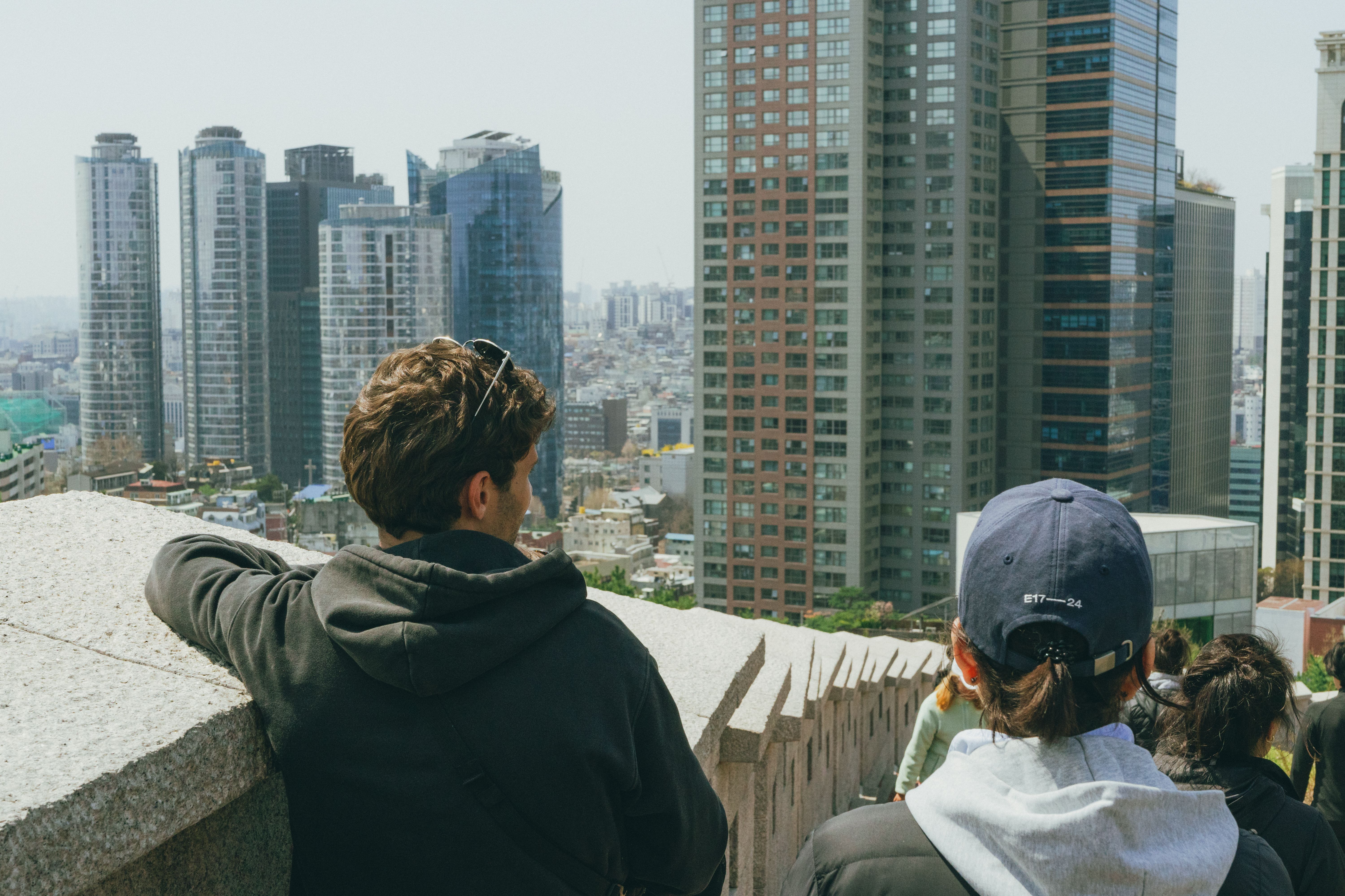 People observing the modern Seoul skyline from an elevated viewpoint.