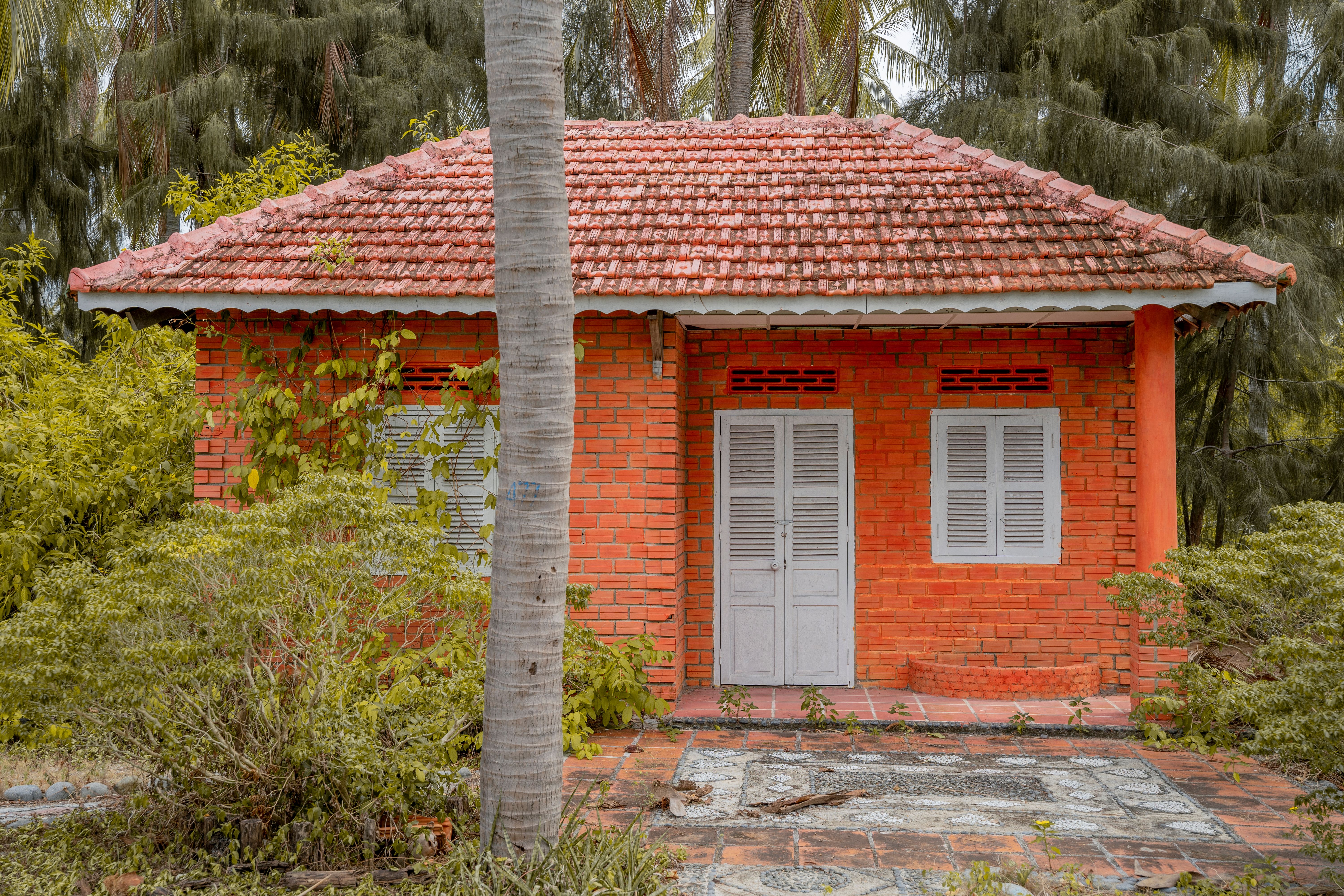 Un cottage traditionnel en briques rouges au milieu d'une végétation luxuriante, parfait pour les retraites rustiques.