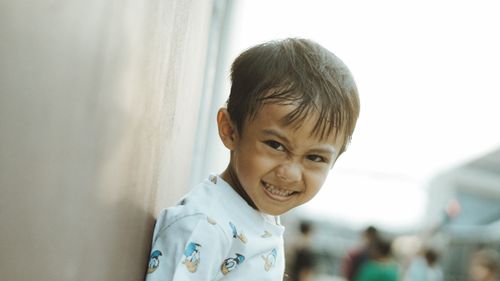 Free A happy child smiling brightly while leaning on a wall outdoors in West Java, Indonesia. Stock Photo