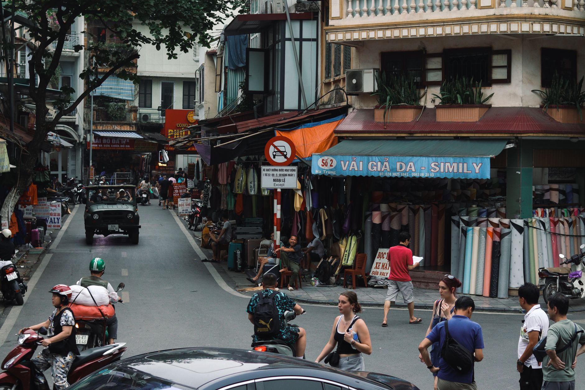 Vibrant street in Hanoi featuring locals shopping, motorbikes, and traditional buildings.