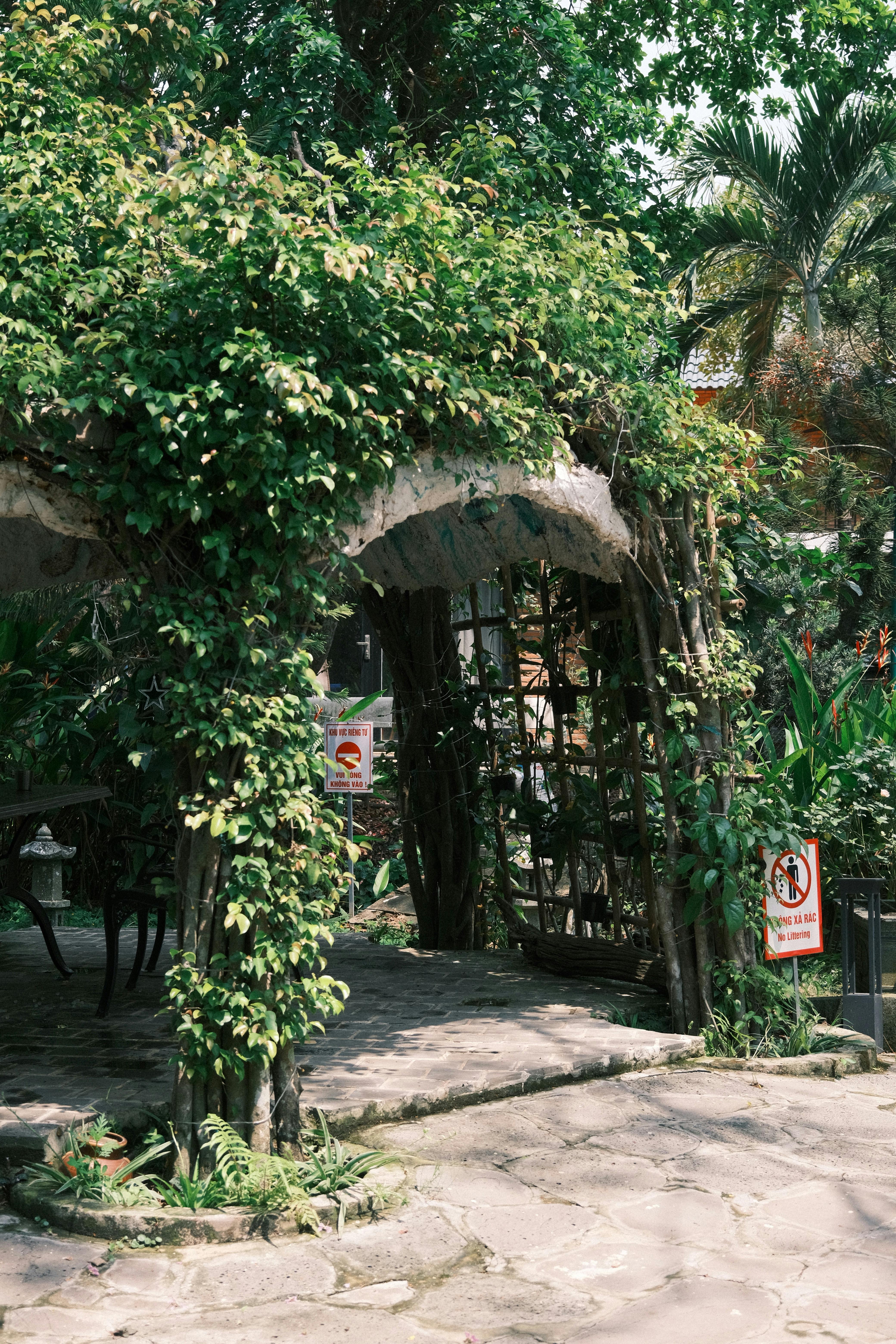 Ücretsiz Yemyeşil bir çardağın süslediği, ferahlatıcı bir dış mekan alanı sunan, pitoresk bir bahçe girişi. Stok Fotoğraflar