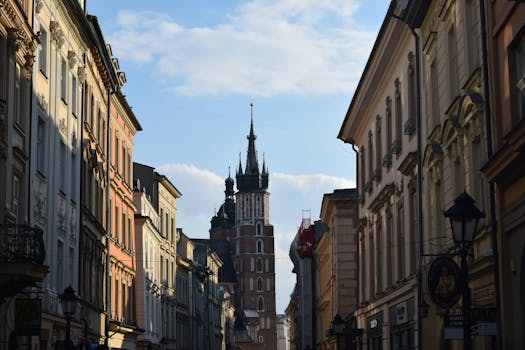 Charming Krakow street with St. Mary's Basilica, capturing historic architecture under a bright sky.